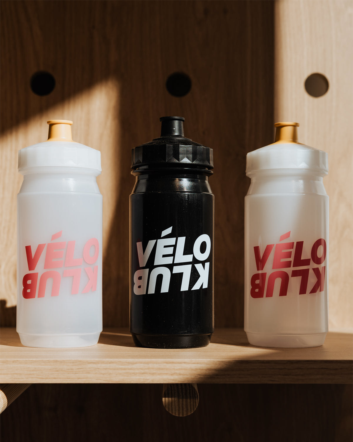 Vélo Klub bidons on a wooden shelf